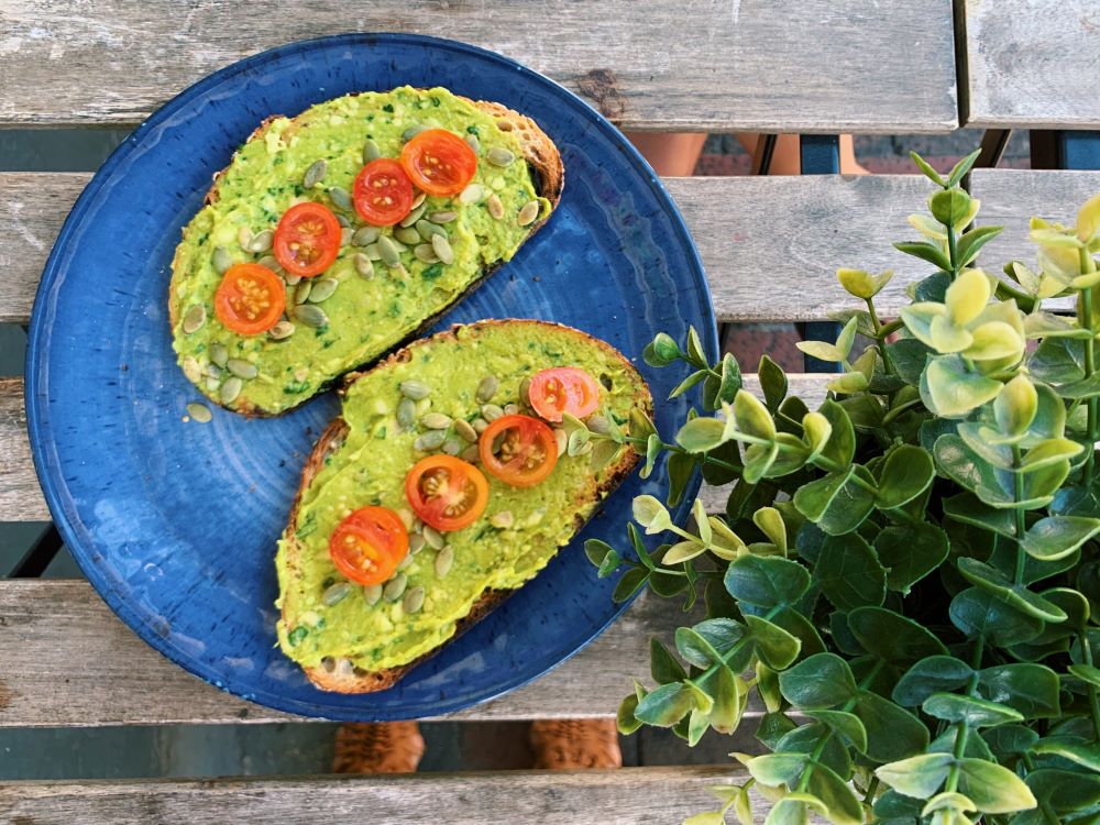Avocado toast and plants on a wood table.