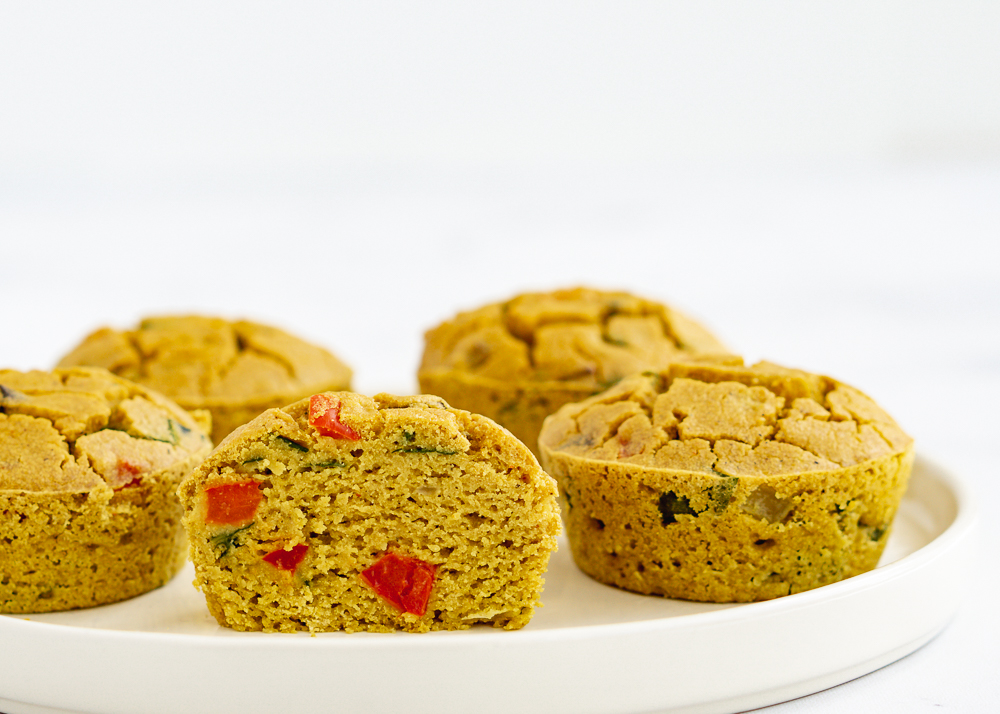 5 chickpea frittata muffins on a white plate with one cut in half