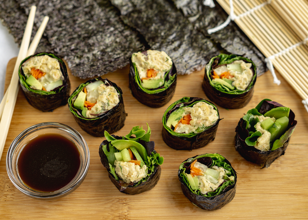 Overhead shot of 8 homemade vegan sushi rolls on a wood board with soy sauce and chopsticks