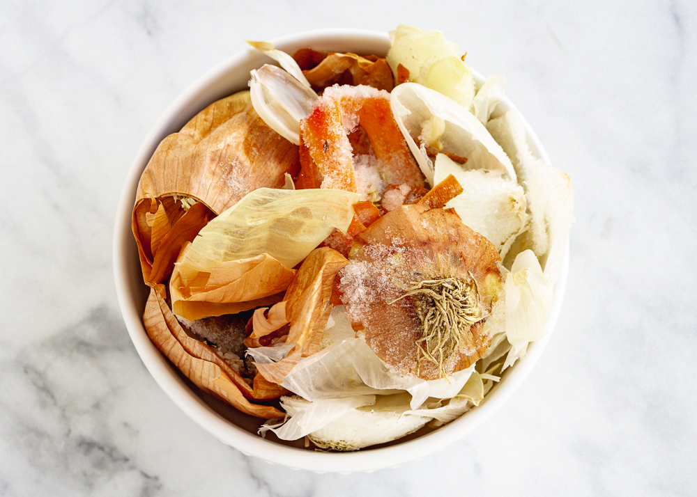 Homemade vegetable broth scraps in a bowl on a marble background