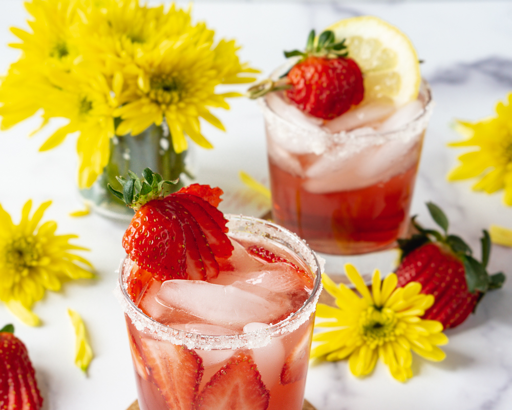Two strawberry hibiscus rosé mocktails with a fresh bouquet of flowers