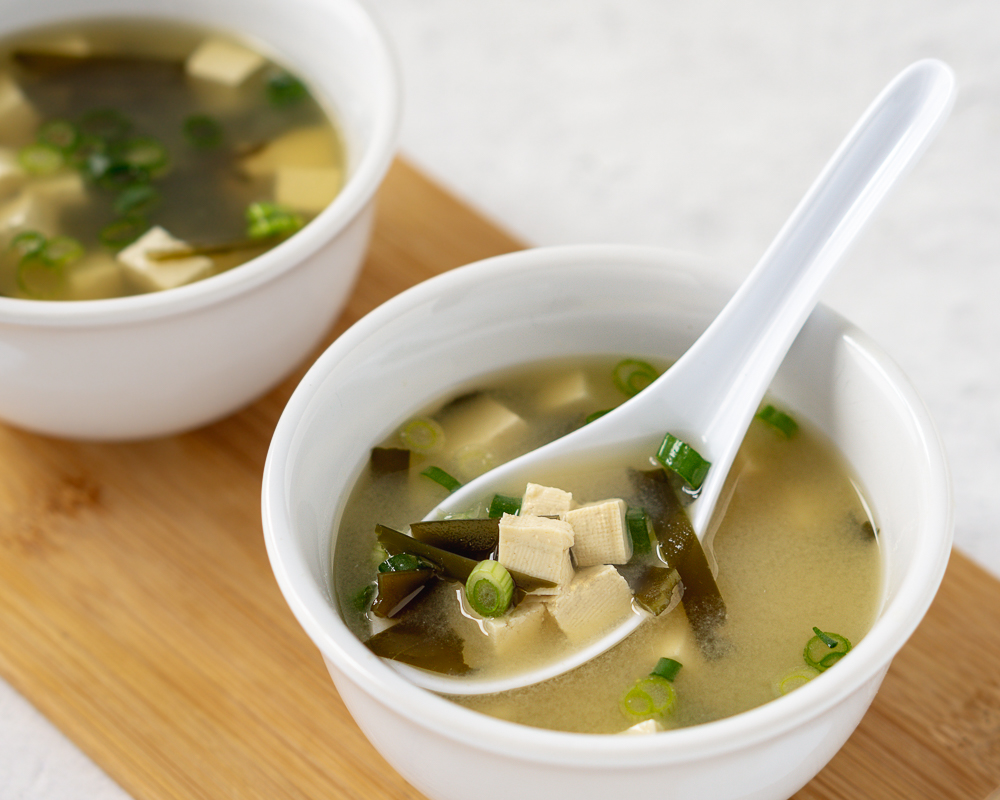 Two bowls of vegetarian miso soup on a cutting board